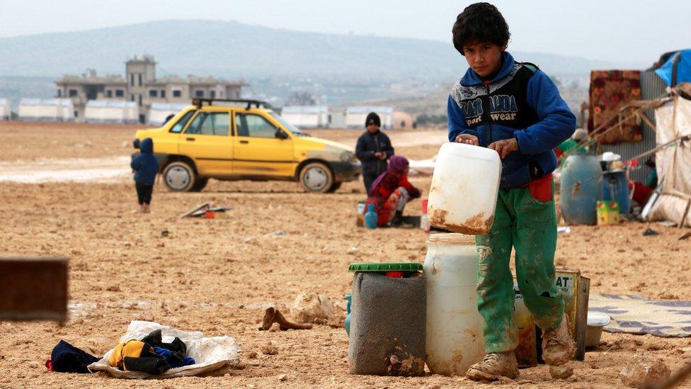 A displaced boy carries a jerrycan at a makeshift camp near the Bab al-Hawa crossing, on the Syrian-Turkish border (6 January 2018)