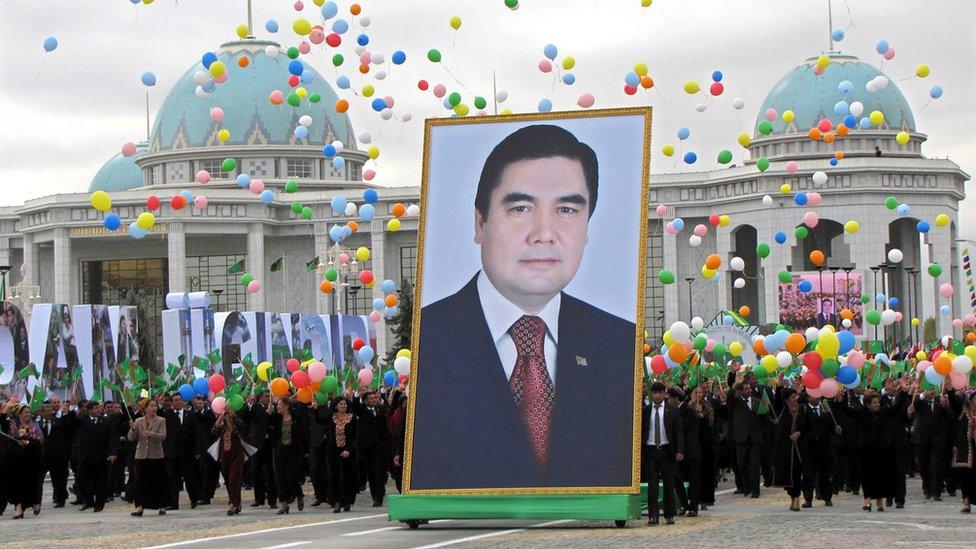 Parade of people holding a photograph of the president