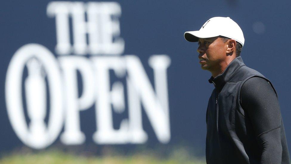 Tiger Woods walks past a sign at Royal Portrush that reads: The Open