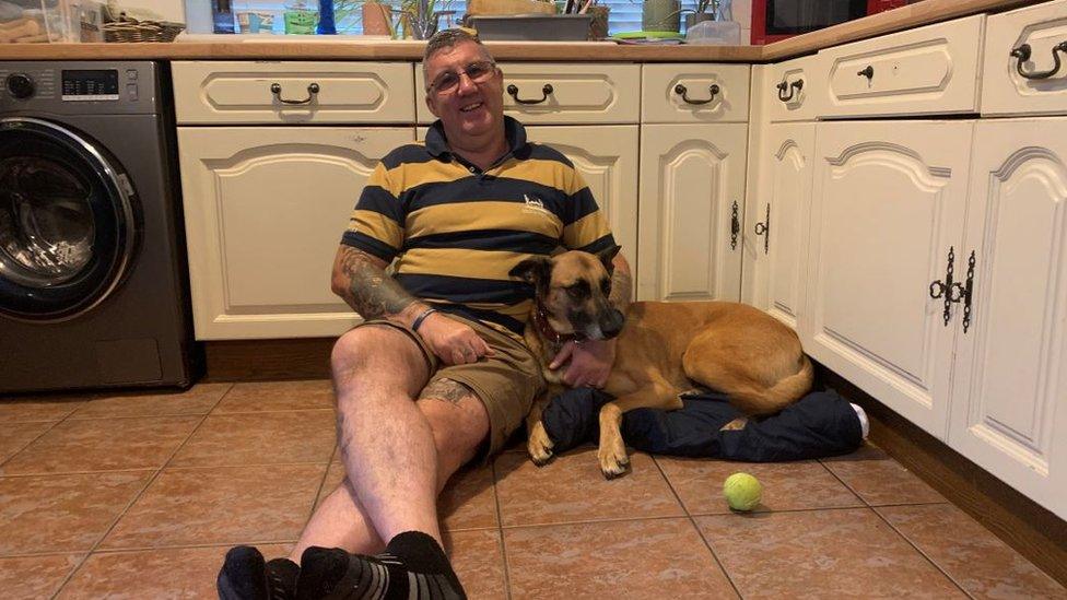 man sitting on floor with dog next to him