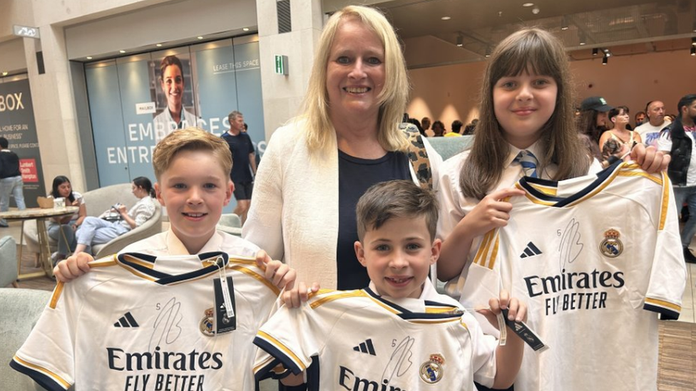 Suzanne Shackleton and three children holding signed Jude Bellingham shirts