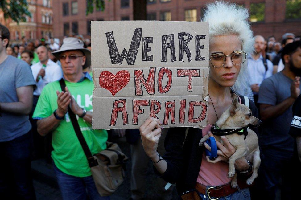 A woman holds a placard at a vigil for the victims of an attack at Manchester Arena