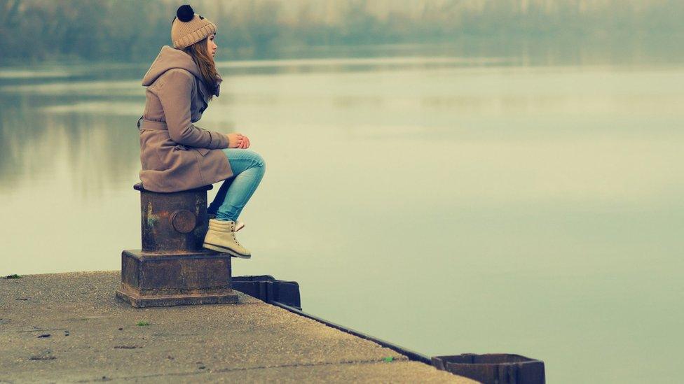 Lonely girl sitting on dock