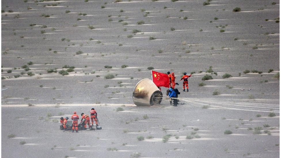 Workers retrieve a re-entry module that was aboard the carrier rocket Long March-7 after it landed in Badain Jaran Desert in northern China, 26 June 2016.