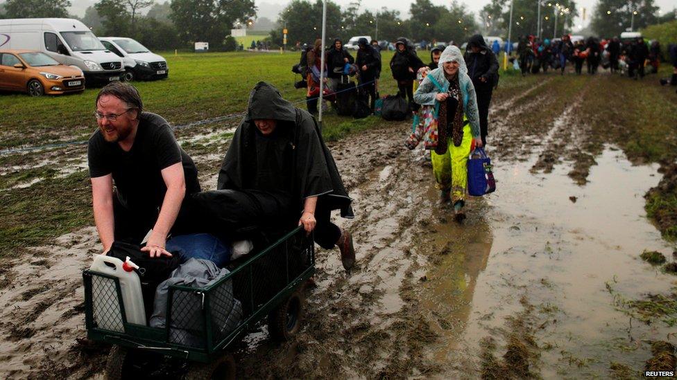 People walking through mud with their luggage