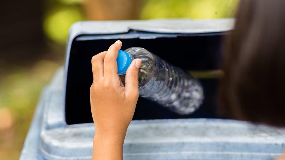 girl putting plastic bottle in bin