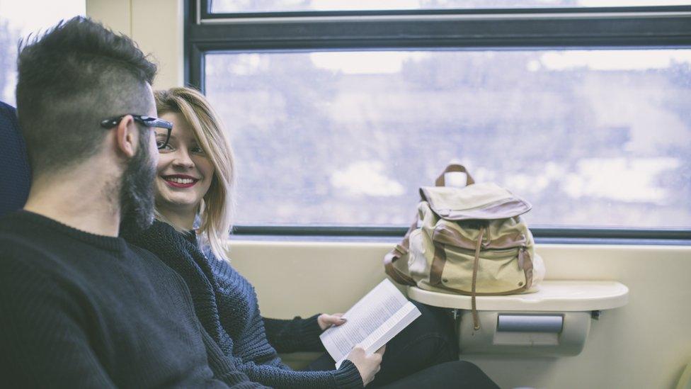 Stock image of a man and woman talking on a train