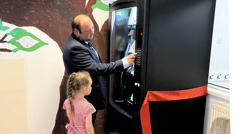 Head teacher Marc Wheeler shows a pupil how to use the book vending machine