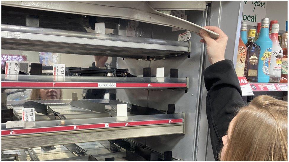 Susan Connolly reaching up to the a smashed part of the cigarette cabinet