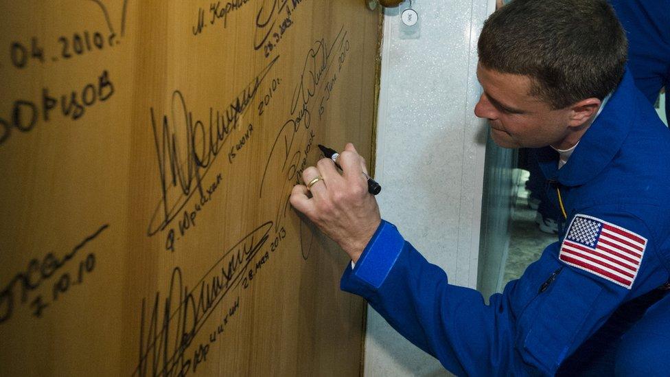 Flight Engineer Reid Wiseman of NASA, performs the traditional door signing at the Cosmonaut Hotel before leaving for launch May 28, 2014