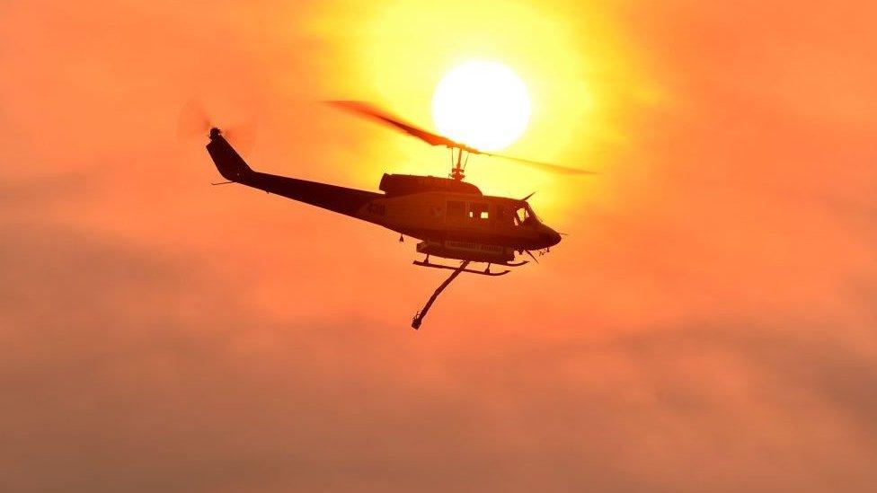 A helicopter prepares to drop water on a large bushfire in Bargo, 150km southwest of Sydney