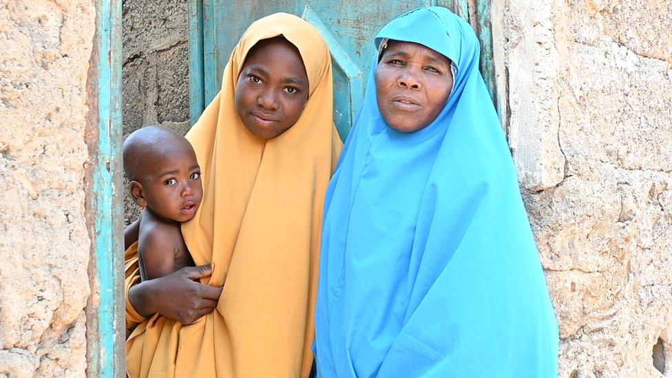 Two women in hijab with one holding a child