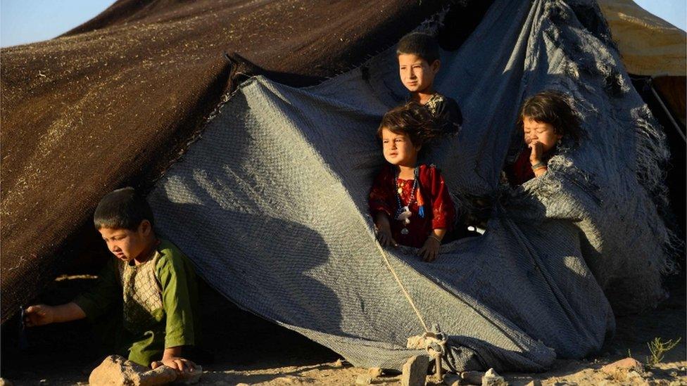 In this photo taken on August 5, 2018, drought-displaced Afghan children look on from their tent at a camp for internally displaced people in Injil district of Herat province.