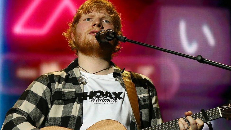 Ed Sheeran playing a guitar on stage