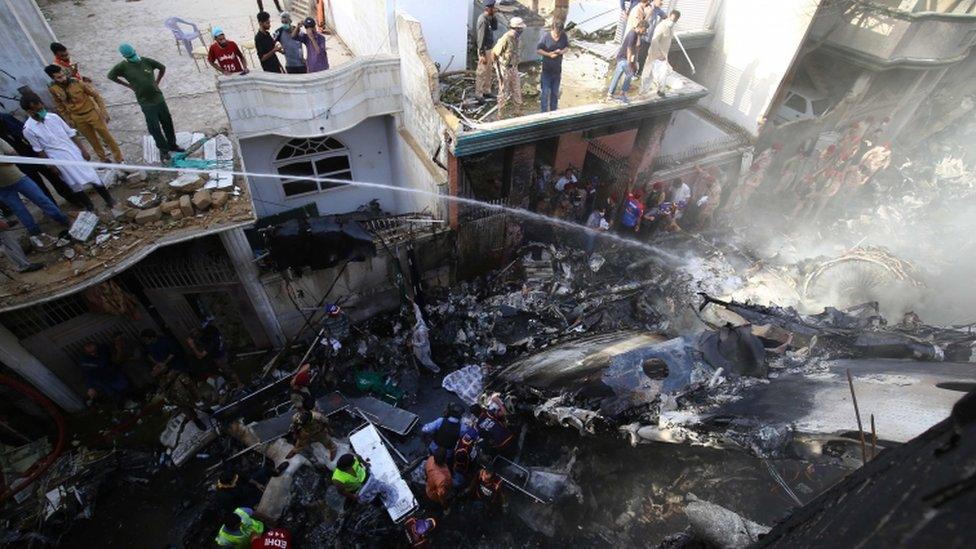 People look down at the burning debris of Flight PK8303