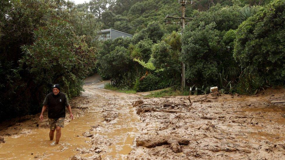 A person walking through deep mud after a landslide in Domain Crescent, Muriwai. Taken on February 14