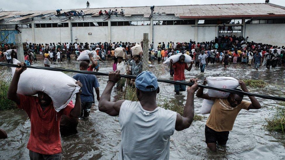 People take sacks of Chinese rice printed "China Aid" from a warehouse surrounded by water after cyclone hit in Beira, Mozambique, on March 20, 2019