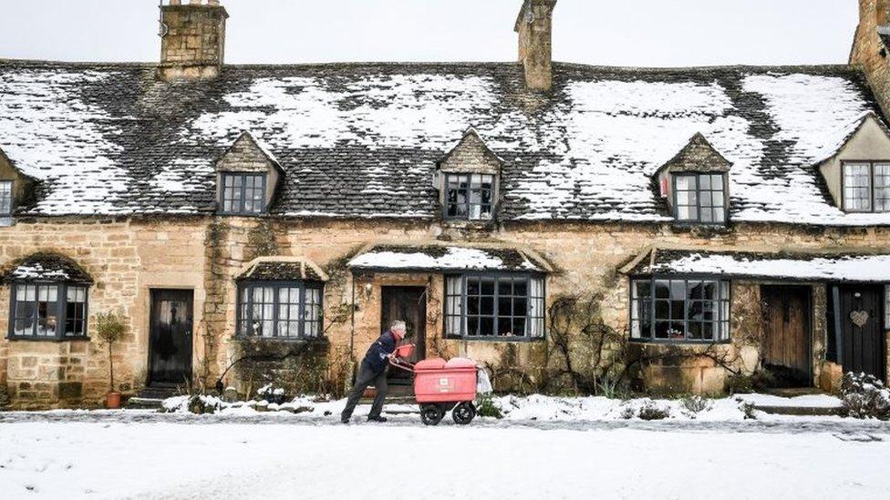 A postman pushing his trolley through snow in Broadway, Worcestershire