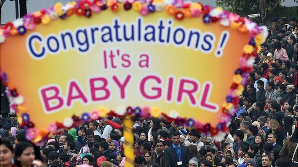 Indian spectators watch as a float carrying a sign that reads "Congratulations! It's a Baby Girl" passes by during the Indian Republic Day parade in Delhi on January 26, 2015