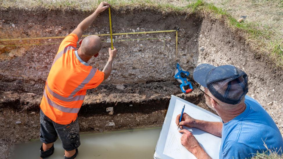 Men measuring and drawing, Warham Camp excavation, 2023