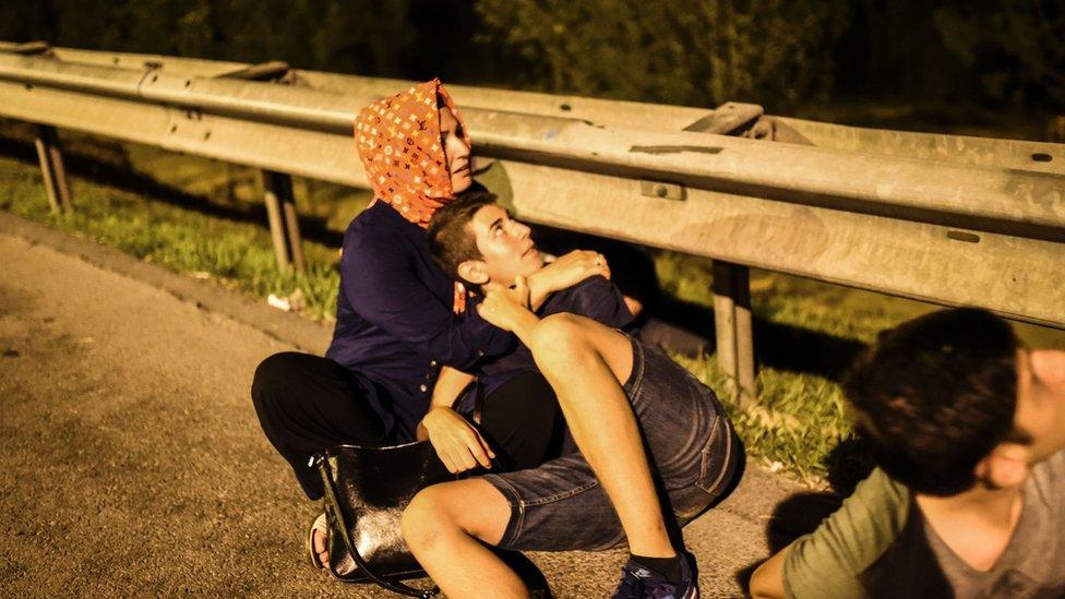 A couple sheltering by the entrance to the Bosphorus Bridge