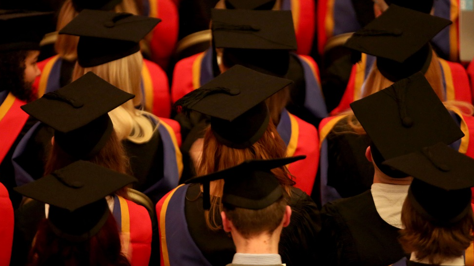 A file photo shows rows of graduates wearing mortar boards and gowns.