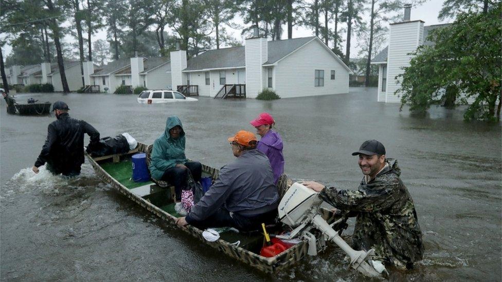 Volunteer rescue boat team with family in flooded neighbourhood