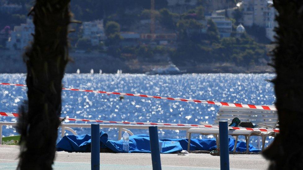 Dead bodies covered with blue sheets are pictured on the Promenade des Anglais seafront in the French Riviera city of Nice on 15 July 2016,