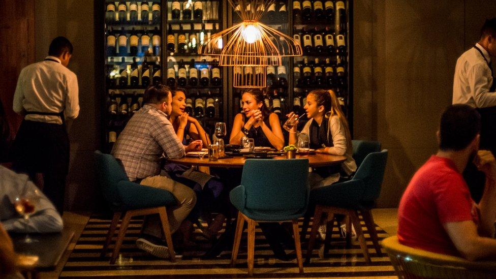 People sit around a table in up-market restaurant in Caracas