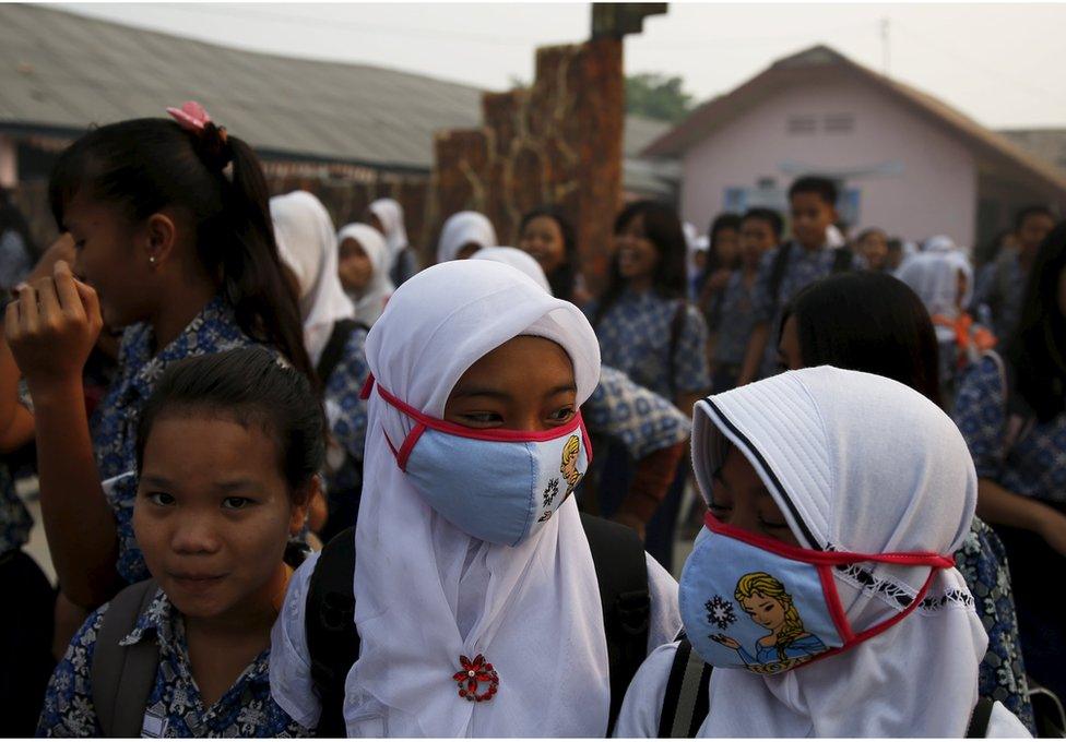 Students, wearing face masks, walk in front of their school as they prepare to head home due to the unhealthy quality of air in Palembang, on Indonesia's Sumatra island, 10 September 2015.