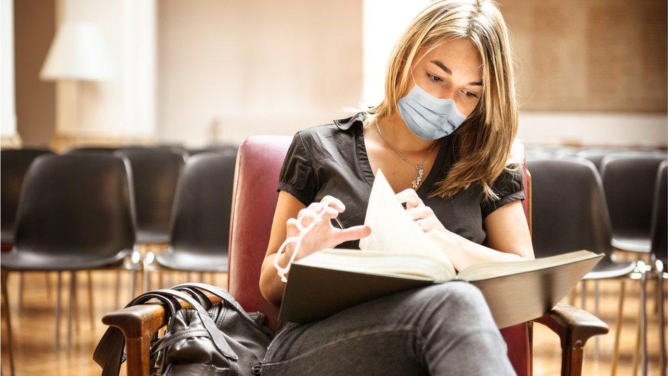 University student reading with mask on