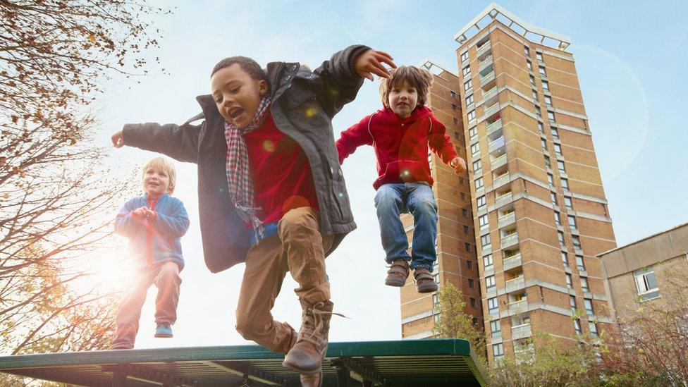 Children-jumping-in-front-of-tower-block.