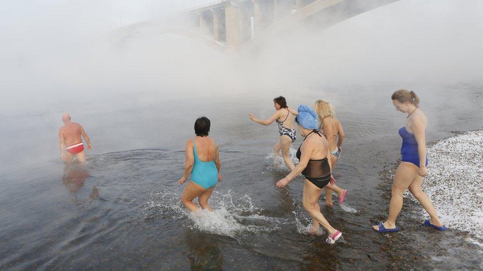 Women follow Mikhail Sashko, chairman and one of the founders of the Cryophile winter swimmers club, into the water