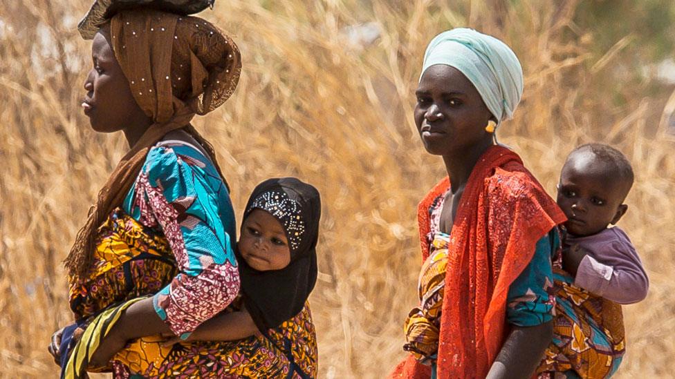 Women in Tamale in Ghana walking each with a baby on their back