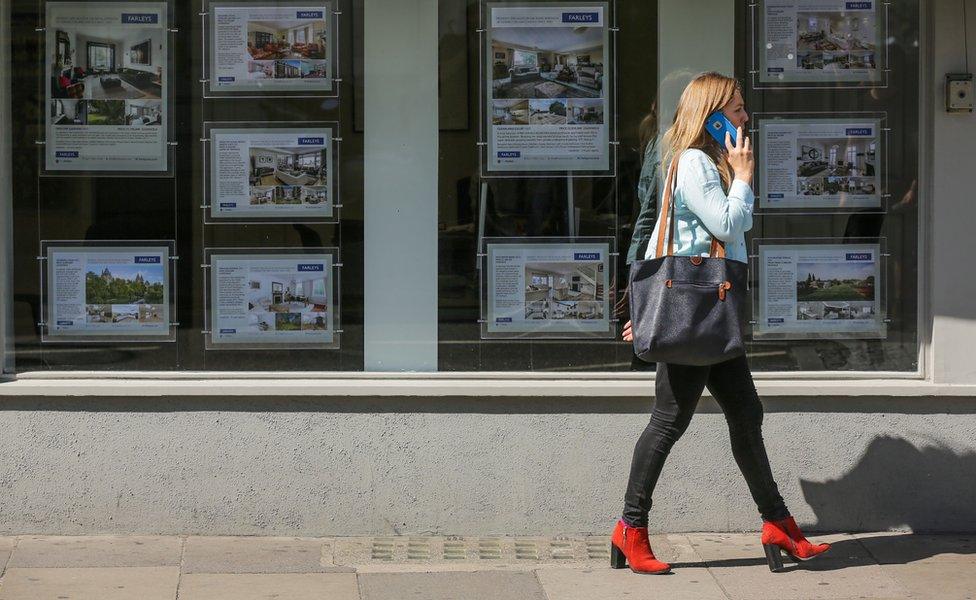 woman walks past estate agents