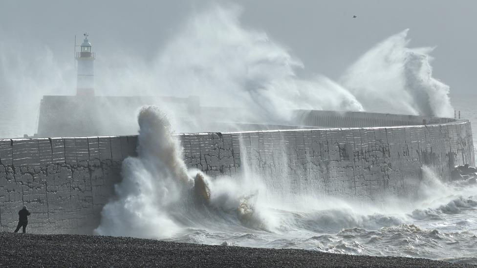 A person views as large waves hit the harbour wall at sunrinse during Storm Isha in Newhaven, southern Britain, on 22 January 2024