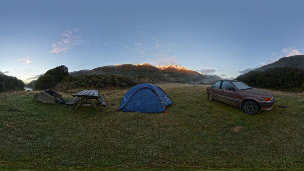 A tent pitched at Cobb River Camp, with a picnic table and car nearby in Kahurangi National Park, New Zealand