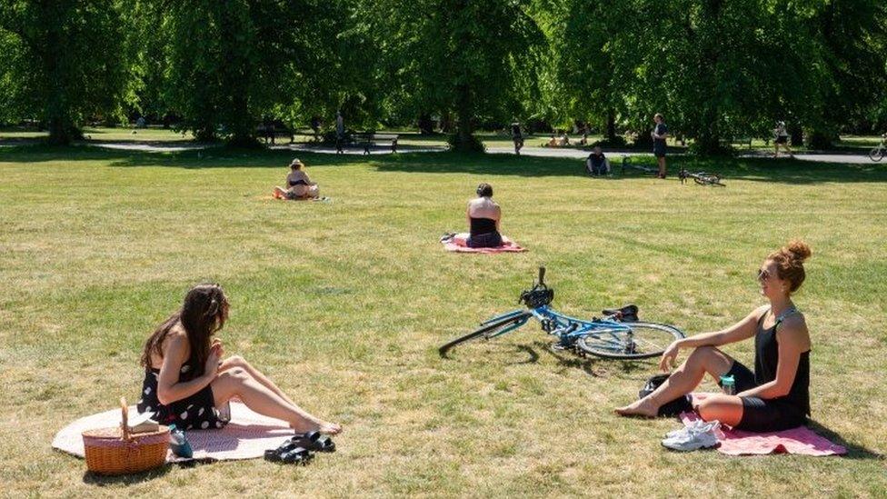 Two women observe social distancing whilst enjoying the hot weather in Greenwich Park, London on Wednesday 20 May