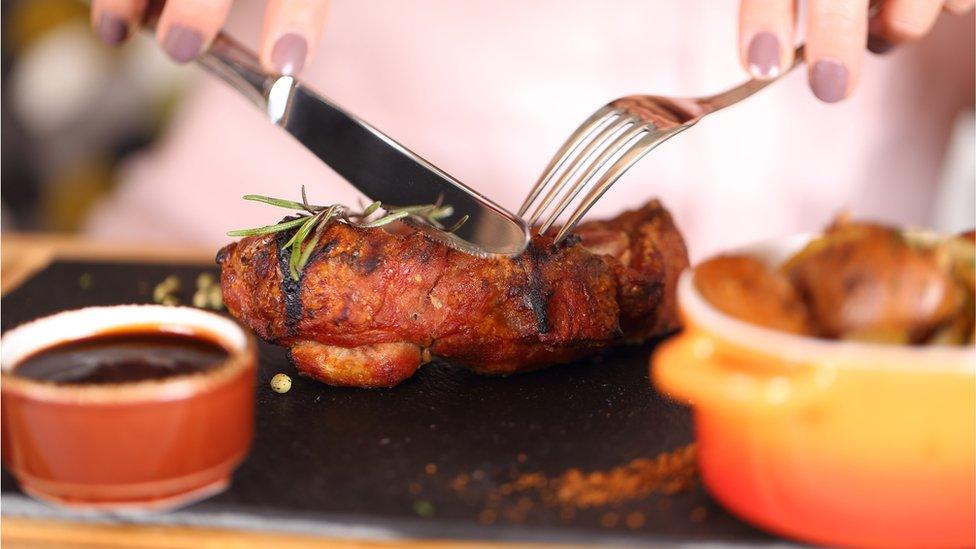 Woman cutting steak with knife and fork