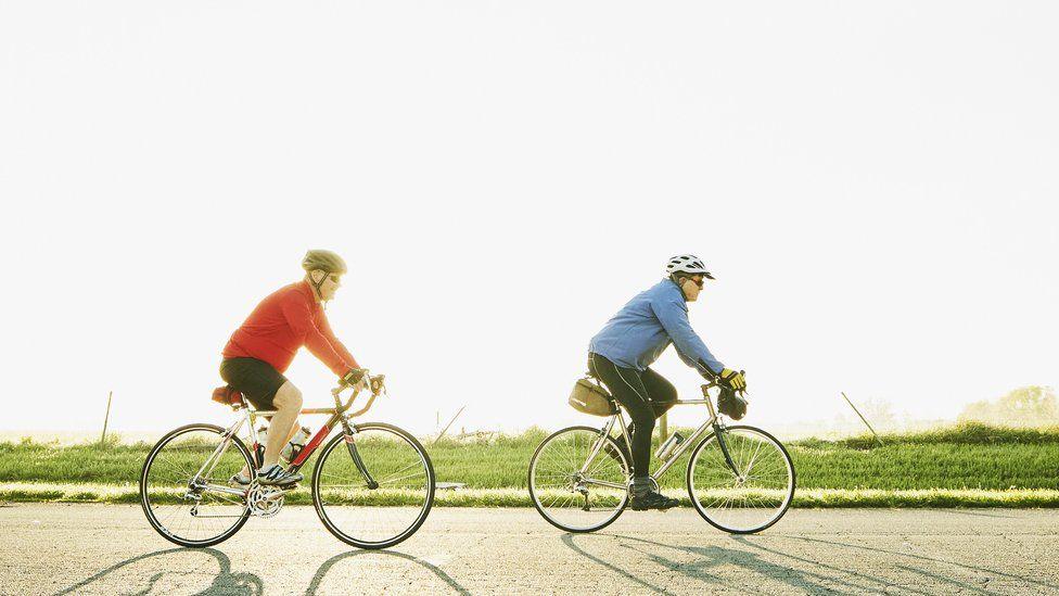 Two cyclists riding along a road