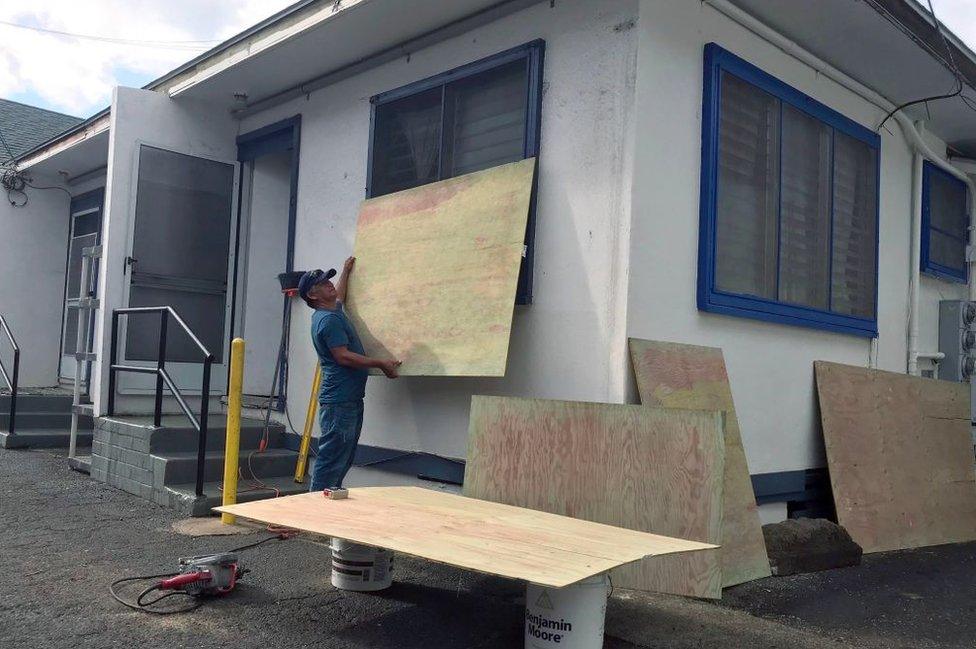 a resident puts wooden planks over windows