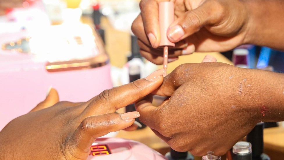 A nail tech painting a woman's hand