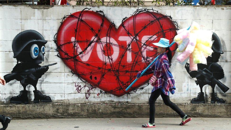 Woman walking past a "Vote" graffiti