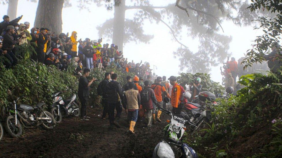 Rescuers help with the evacuation while others watch on