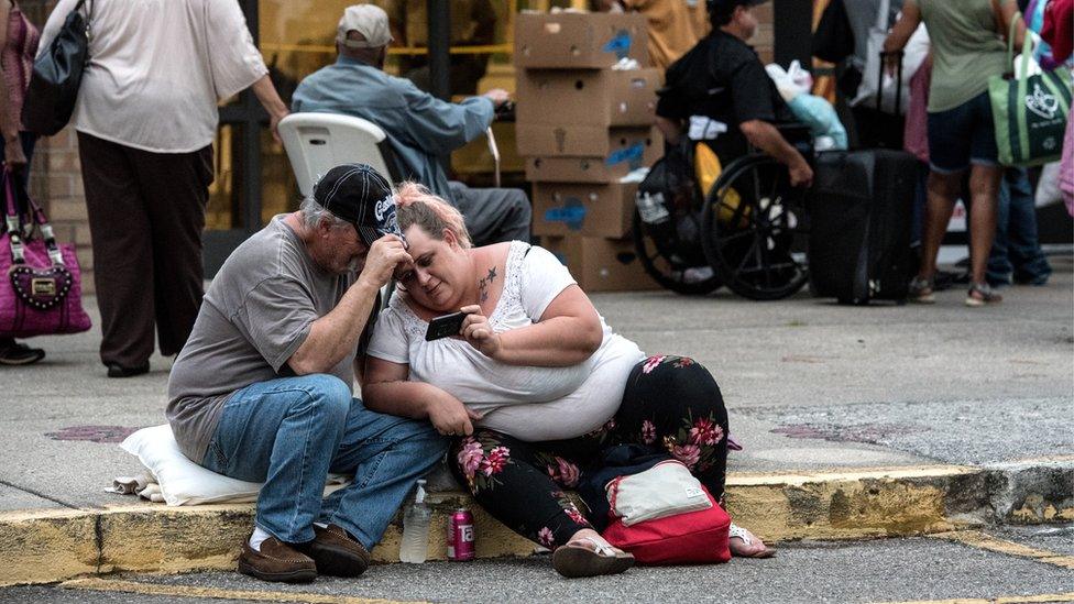 Chuck Ledford (L), watches Looney-Tunes with his daughter Misty as they evacuate in Wilmington, North Carolina