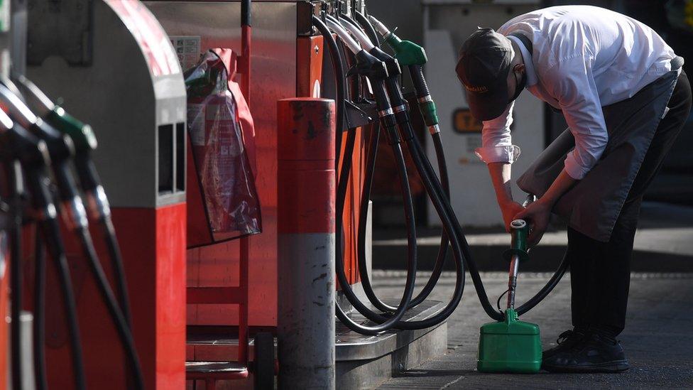 A man fills up a petrol can on a station forecourt