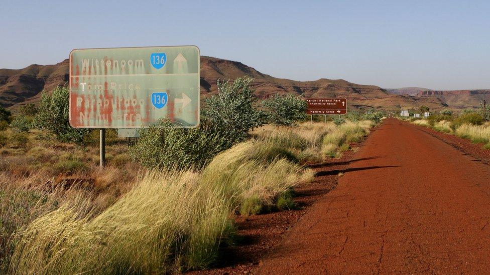 A faded road sign pointing to Wittenoom, and to other towns in the Pilbara area