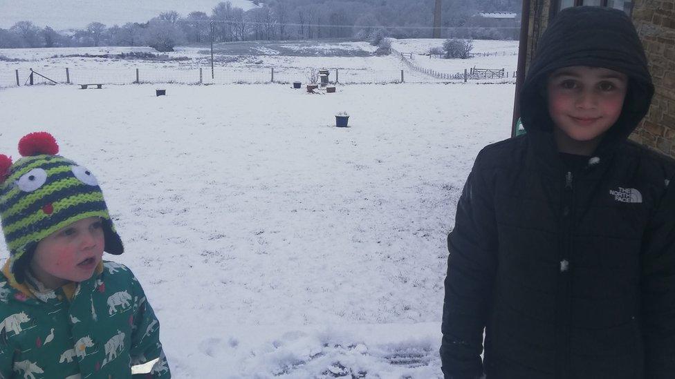 Two children wrapped up warm in snowy field.