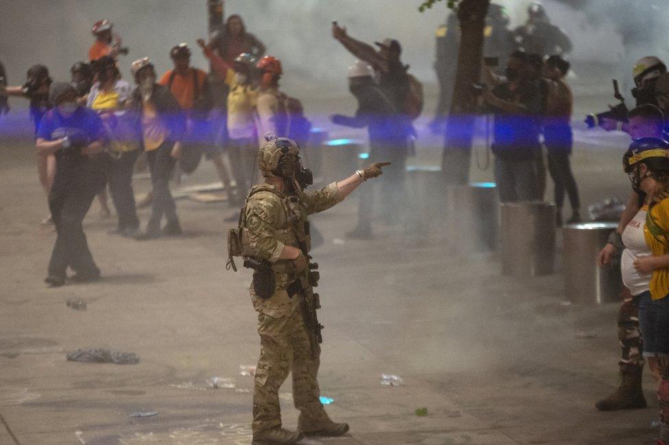 A federal officer points to a protester while clearing the street near the courthouse in Portland where violent clashes erupted