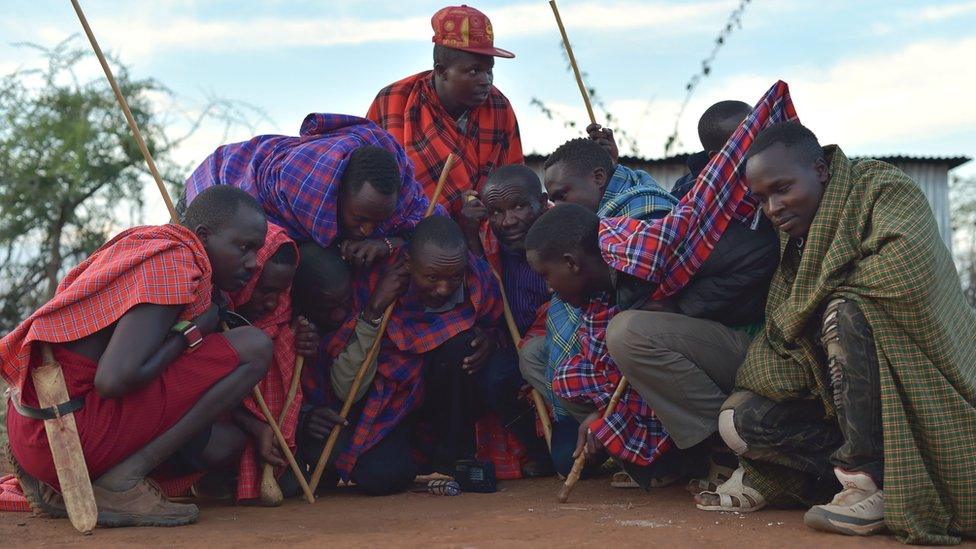 A group of Maasai men crouching around a radio near Saikeri, Kenya - Tuesday 8 November 2016